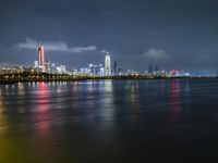 a skyline view of a city at night reflected in the water of lake michigan, with light - up buildings