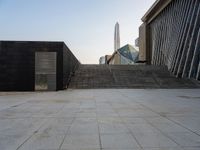 the stairs are leading into a building and a large skyscraper rises in the distance over the stairs