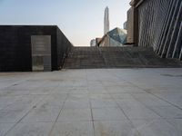 the stairs are leading into a building and a large skyscraper rises in the distance over the stairs