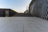 the stairs are leading into a building and a large skyscraper rises in the distance over the stairs