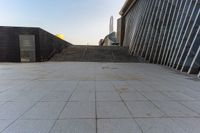 the stairs are leading into a building and a large skyscraper rises in the distance over the stairs