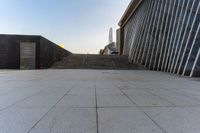 the stairs are leading into a building and a large skyscraper rises in the distance over the stairs