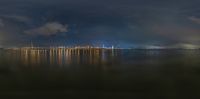 the lights are reflecting on the water under a dark sky above the skyline and building