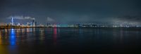 a view of an open city by the water at night time with lights reflected on the water