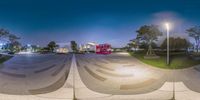 a street corner that has some stairs and trees near it at night as seen in a fish eye lens