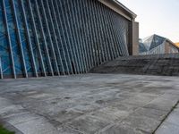 a person walking on the pavement in front of a tall building with stairs down the middle