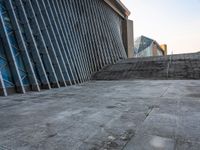 a person walking on the pavement in front of a tall building with stairs down the middle