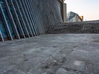 a person walking on the pavement in front of a tall building with stairs down the middle