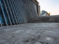 a person walking on the pavement in front of a tall building with stairs down the middle