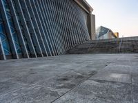 a person walking on the pavement in front of a tall building with stairs down the middle