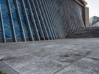 a person walking on the pavement in front of a tall building with stairs down the middle