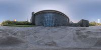 a circular fountain sits inside of a circular building with a stone patio in front of it