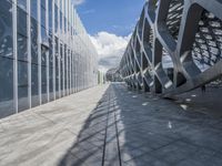 a walkway between two buildings in a big city with blue skies overhead and clouds above
