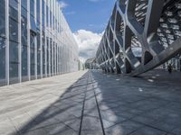 a walkway between two buildings in a big city with blue skies overhead and clouds above