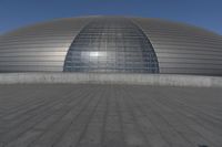 a person on a skateboard in front of a big building with a curved roof