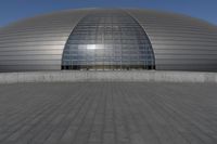 a person on a skateboard in front of a big building with a curved roof