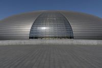 a person on a skateboard in front of a big building with a curved roof