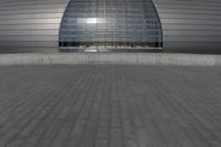 a person on a skateboard in front of a big building with a curved roof