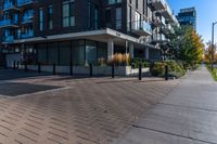 a person walks down a brick walkway in front of an apartment complex with an awning,