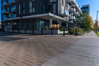 a person walks down a brick walkway in front of an apartment complex with an awning,