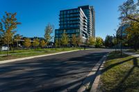 there is a tall building that sits near the road in front of it, and has many trees