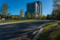 there is a tall building that sits near the road in front of it, and has many trees