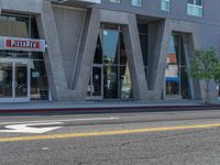 a woman riding a skateboard past a commercial building in an urban area of los