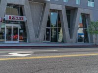 a woman riding a skateboard past a commercial building in an urban area of los