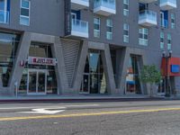 a woman riding a skateboard past a commercial building in an urban area of los