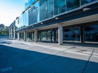 an empty sidewalk on the side of a building with glass doors and railings that are connected