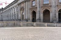 an empty sidewalk in front of a stone building with a statue on it and tall columns