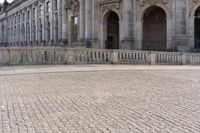 an empty sidewalk in front of a stone building with a statue on it and tall columns