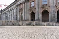 an empty sidewalk in front of a stone building with a statue on it and tall columns