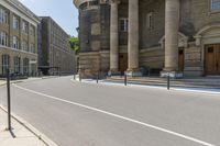 a long sidewalk in front of a building that has columns and columns behind it, along with a bench