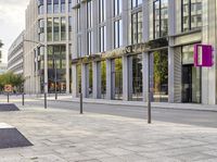 a sidewalk on the corner with benches and trees on both sides of it with people walking