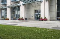 a sidewalk leading to a government building with flower display on the windows of the front entrance