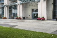 a sidewalk leading to a government building with flower display on the windows of the front entrance