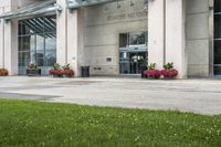 a sidewalk leading to a government building with flower display on the windows of the front entrance