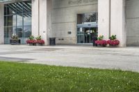 a sidewalk leading to a government building with flower display on the windows of the front entrance