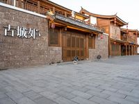 people walk on a sidewalk next to a stone building with chinese writing and decorations on it