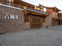 people walk on a sidewalk next to a stone building with chinese writing and decorations on it