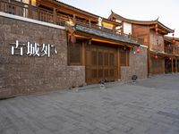 people walk on a sidewalk next to a stone building with chinese writing and decorations on it