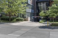 a sidewalk with no traffic on it near tall buildings and a street corner with trees