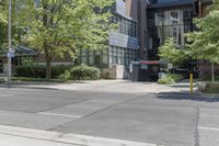 a sidewalk with no traffic on it near tall buildings and a street corner with trees