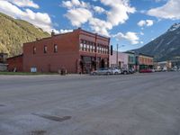 a red fire hydrant sitting in front of an old store window and building next to an open air field