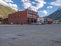 a red fire hydrant sitting in front of an old store window and building next to an open air field