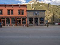 a red fire hydrant sitting in front of an old store window and building next to an open air field