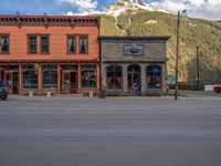 a red fire hydrant sitting in front of an old store window and building next to an open air field