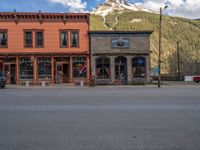 a red fire hydrant sitting in front of an old store window and building next to an open air field