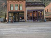 a red fire hydrant sitting in front of an old store window and building next to an open air field